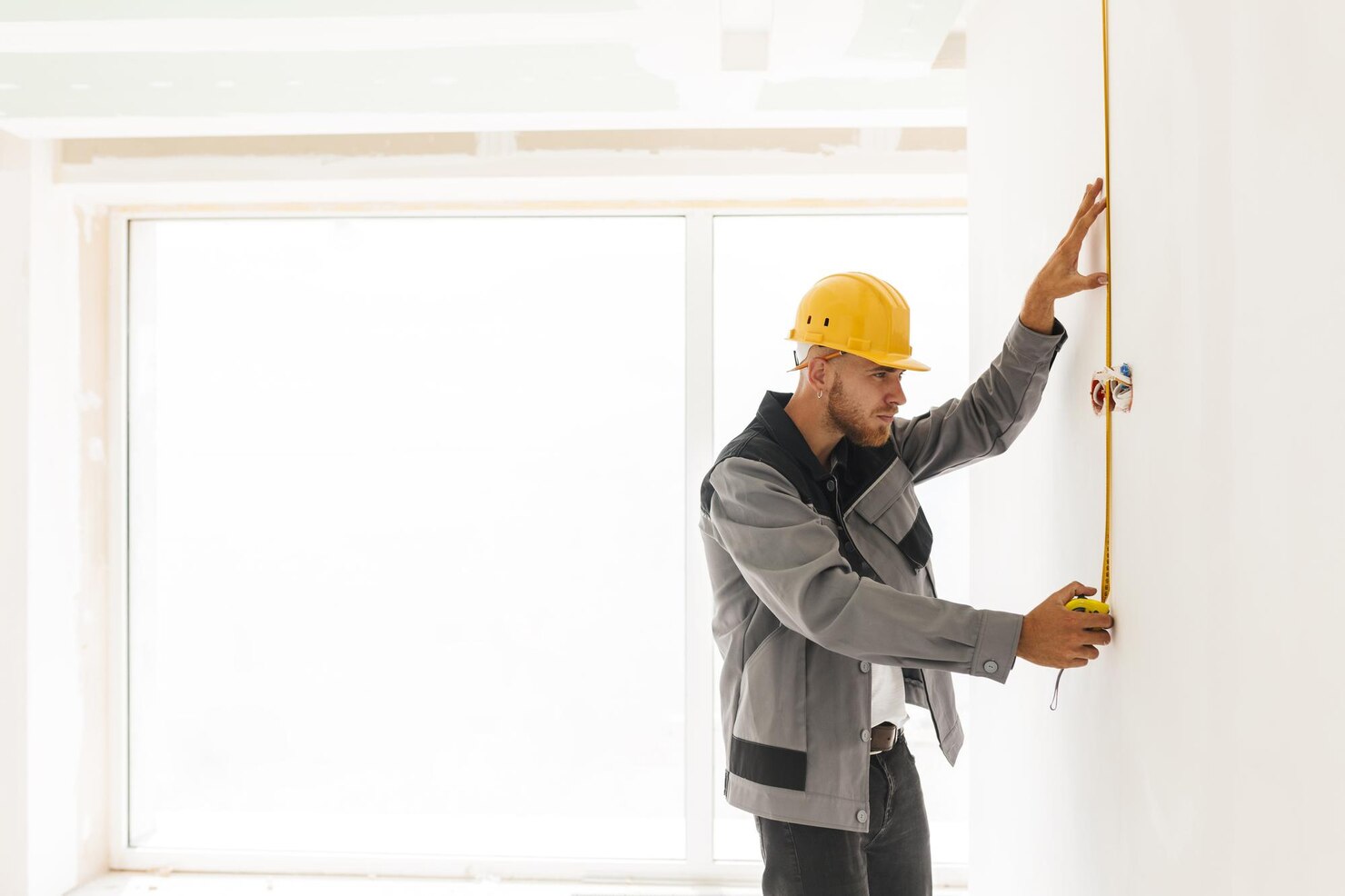 joven constructor ropa trabajo casco amarillo usando cinta metrica reparacion piso gran ventana fondo 574295 1600